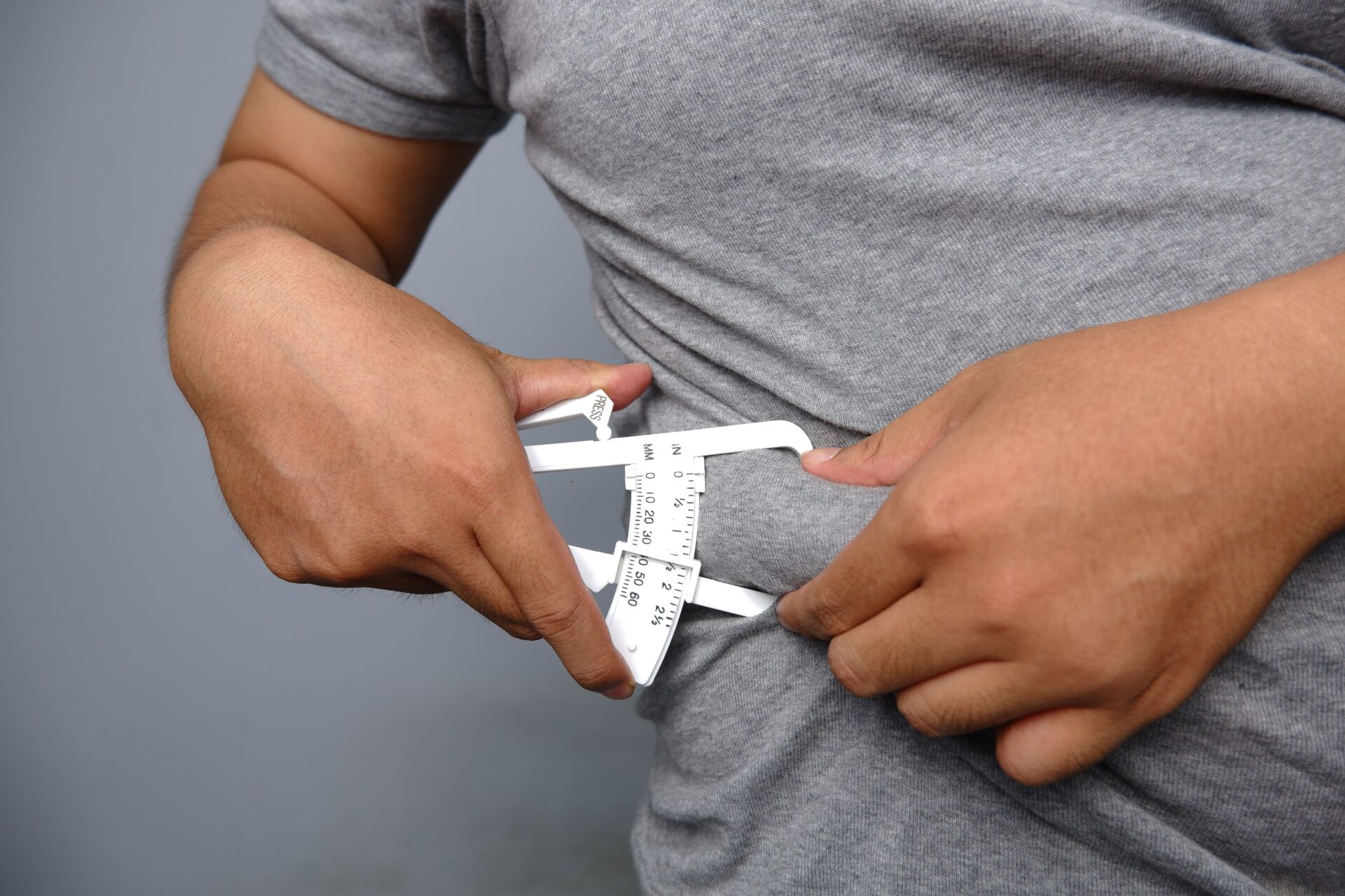 Man using Calliper tool too measure his body fat